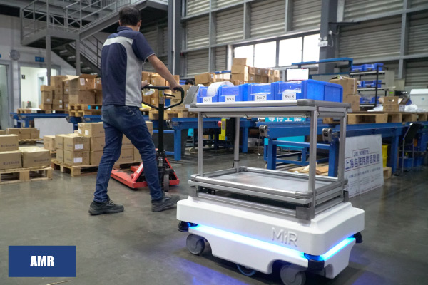 AMR robot working in the same area as a human worker AMR with shelf on top working in same area as a human worker